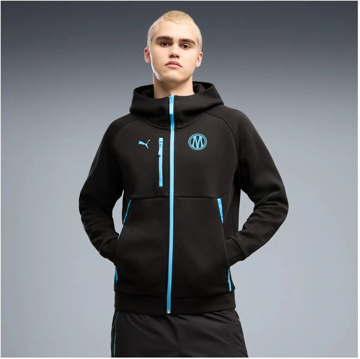 Veste à capuche OM PumaTech noire portée, zips bleu ciel
