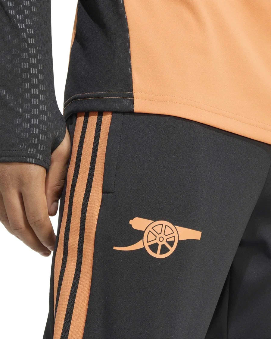 Pantalon d'entraînement Arsenal noir, canon et bandes orange, porté sous le haut assorti