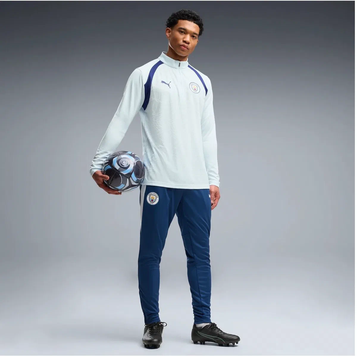 Haut d’entraînement Manchester City bleu ciel et pantalon marine à bande blanche portés