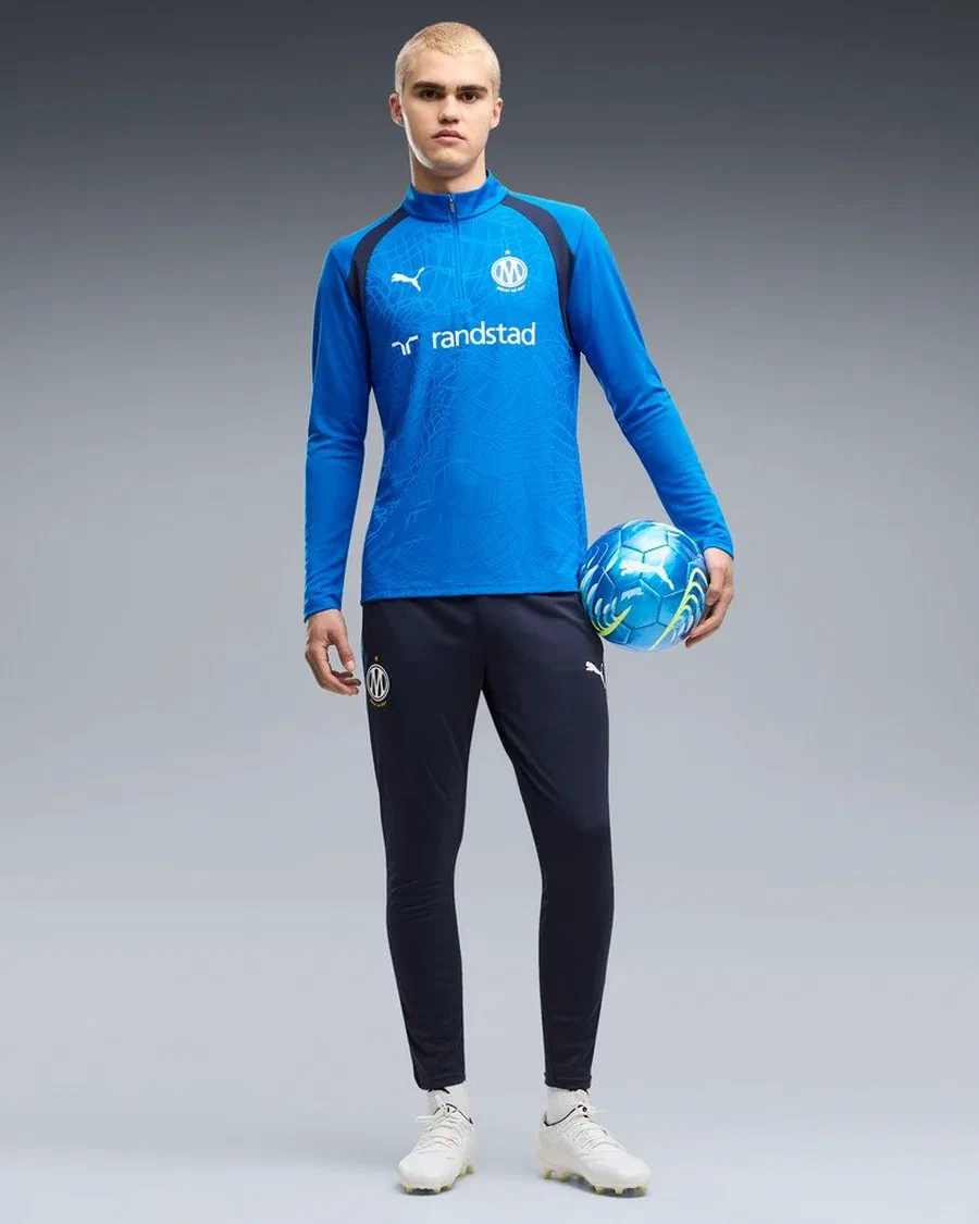 Haut d'entraînement OM 2026/27 bleu roi et pantalon marine portés, ballon à la main